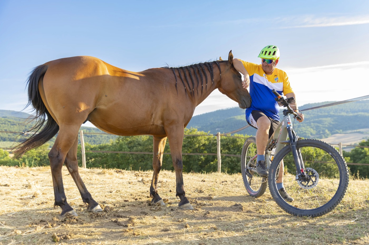Ciclista in sosta accanto a un cavallo su un crinale panoramico