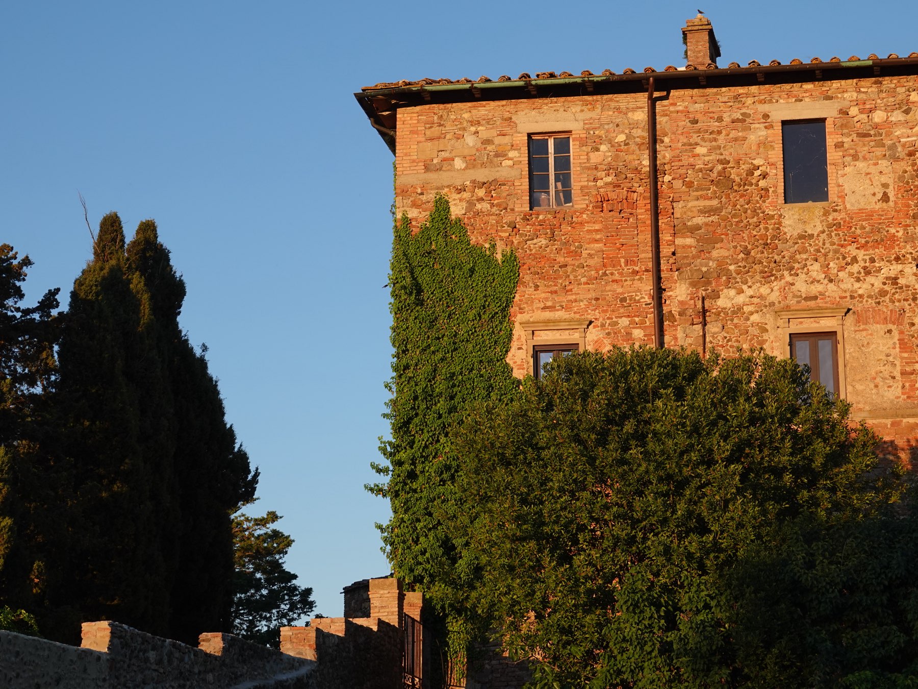 Il borgo in pietra e mattoni della tenuta all'ora dorata, tra cipressi ed edera