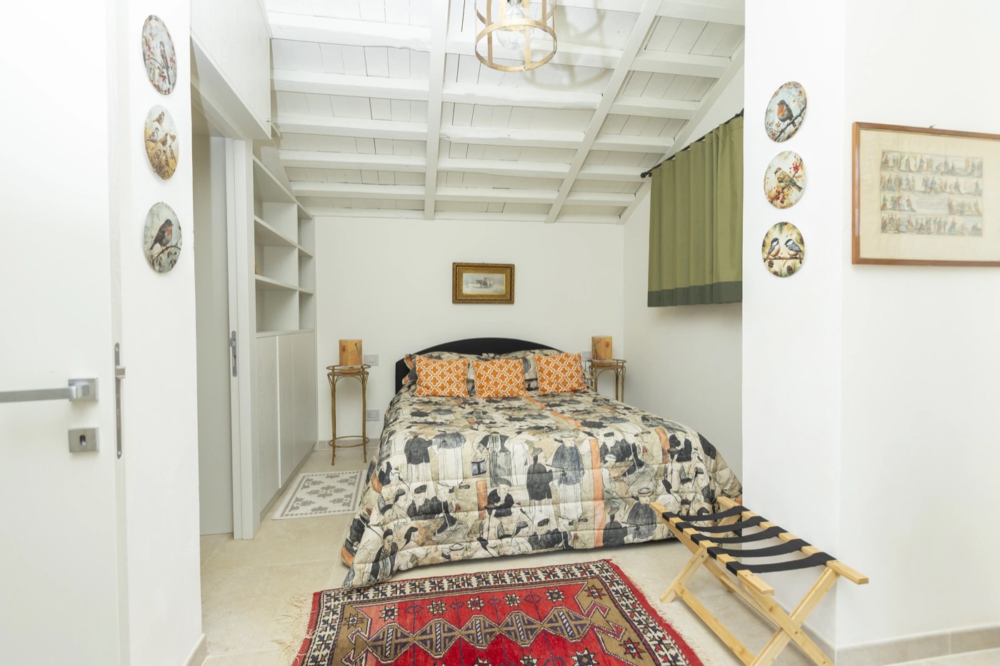 La camera del Podere Capannina con travi bianche, piatti decorativi e tappeto kilim