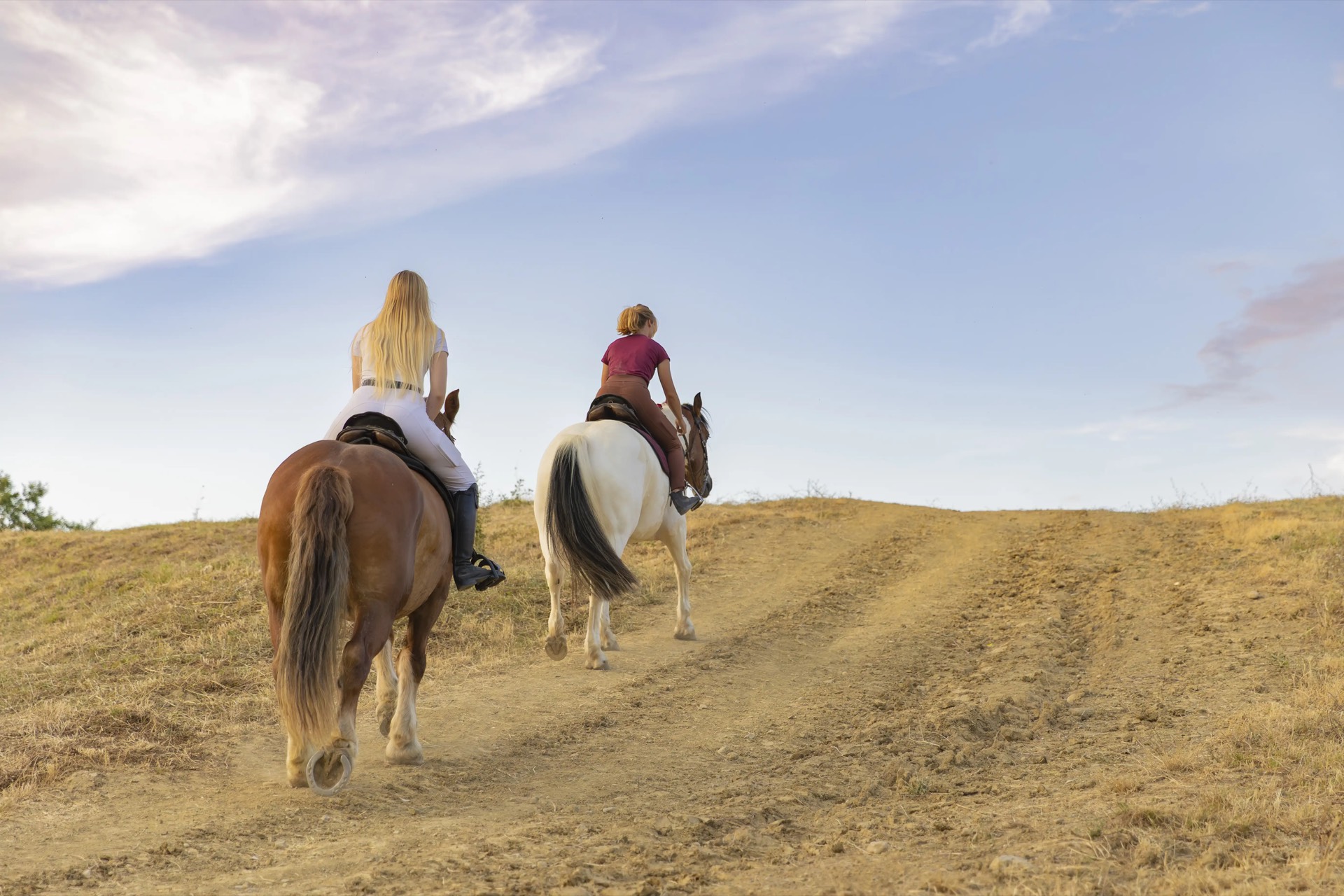 Due cavalieri risalgono una strada sterrata nella campagna senese