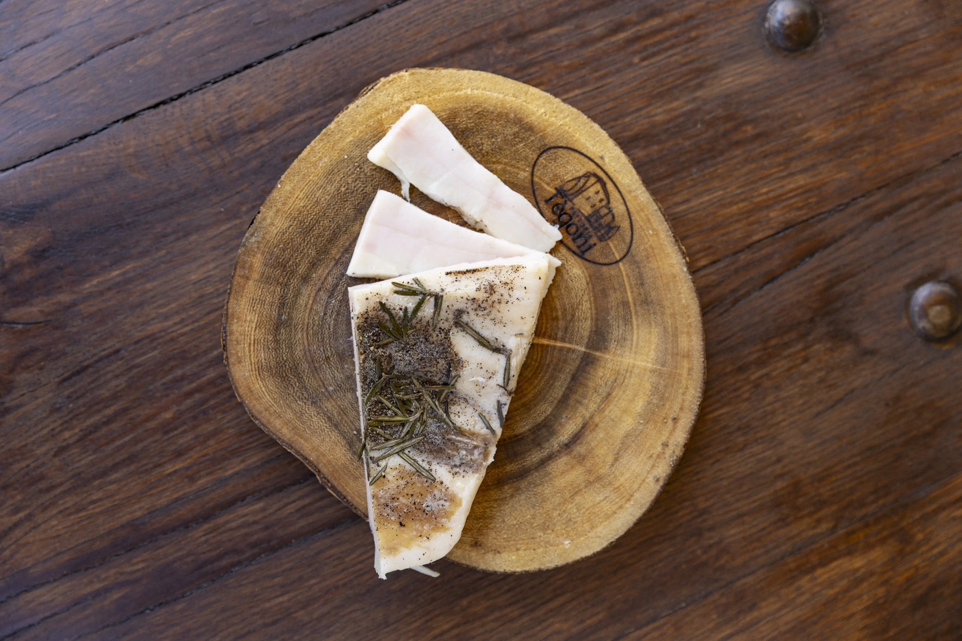 Lardo alle erbe su tagliere di legno, still-life dei salumi