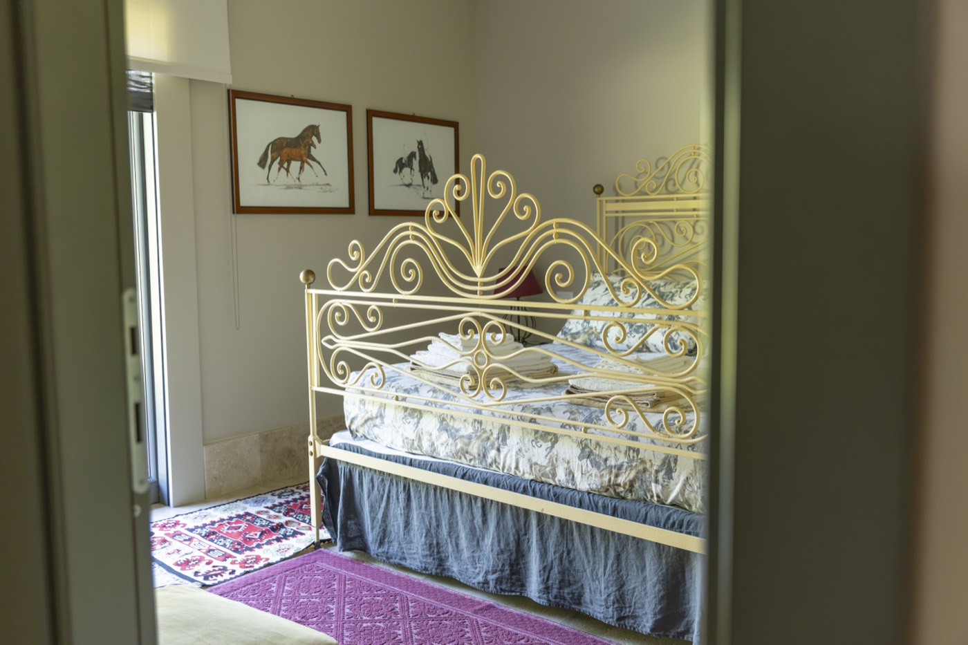 Camera da letto di Villa Airone con letto in ferro battuto e stampe di cavalli